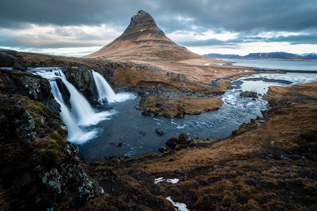An aerial photo from Iceland, the feminist paradise: a mountain with two waterfalls and a river flowing in front
